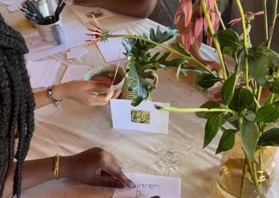 Hands drawing and designing around a table adorned with freshly cut flowers